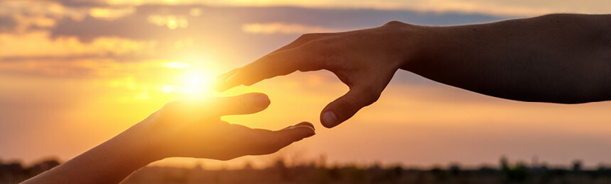 Hands Reaching Out in Front of Sunset