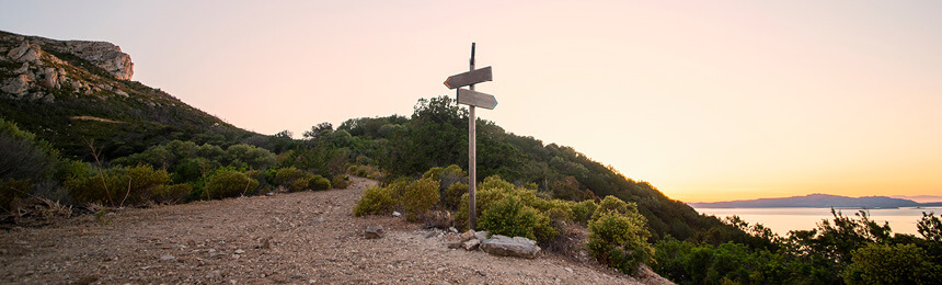 Sign Post Indicating Two Paths on Mountain at Sunset